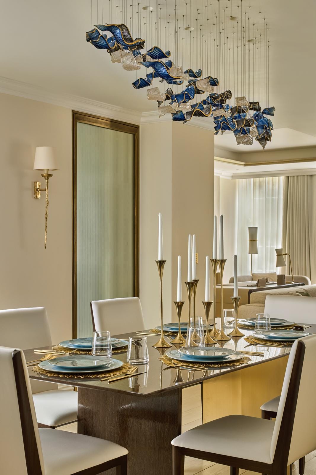 Dining setting framed by soft drapery beneath a sculptural glass ceiling light.