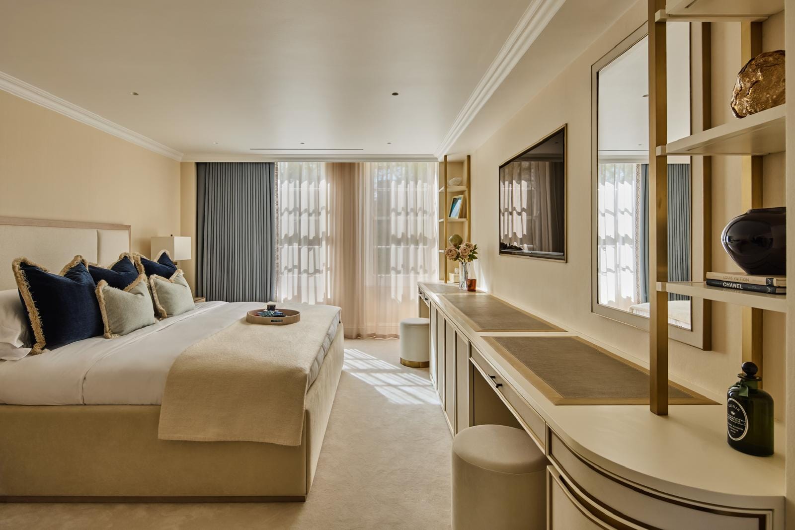 Principal bedroom with layered bedding, integrated shelving and a dressing table.