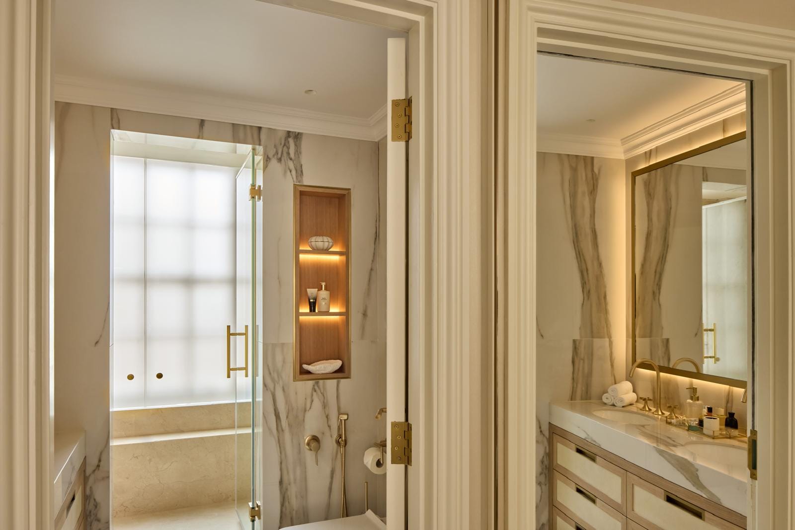 Principal bathroom in book-matched marble with brass fittings and a walk-in shower.