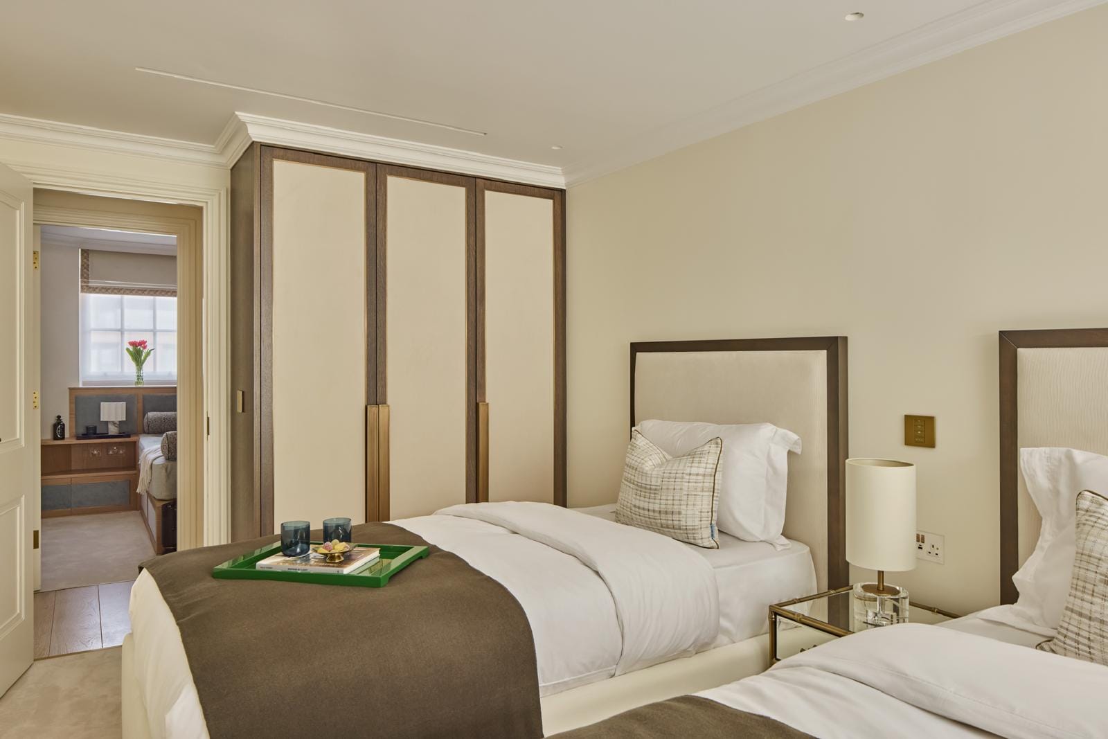 A twin bedroom with matching beds, fitted wardrobes and an ensuite glimpsed beyond.